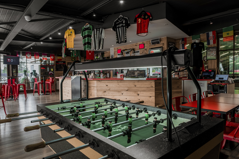 Baby-foot devant le bar du club house, maillots suspendus au plafond