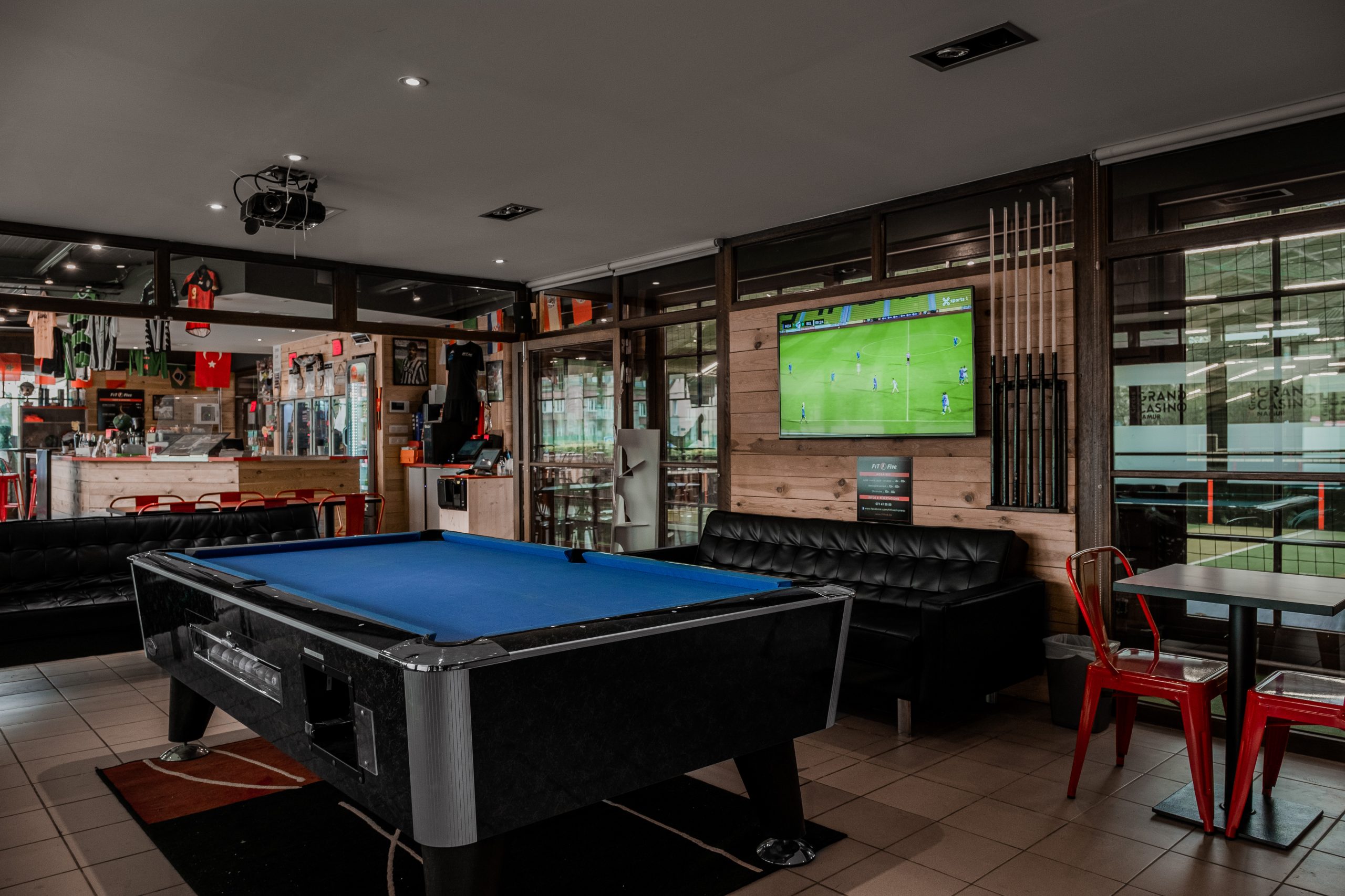 Club house Fit Five : billard, écran diffusant un match et bar en bois