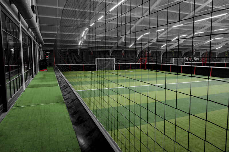 Terrain de foot à 5 en gazon synthétique derrière un grillage